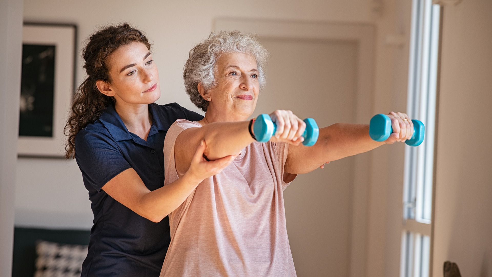 Ältere Frau beim Training mit Hanteln zusammen mit einem Physiotherapeuten