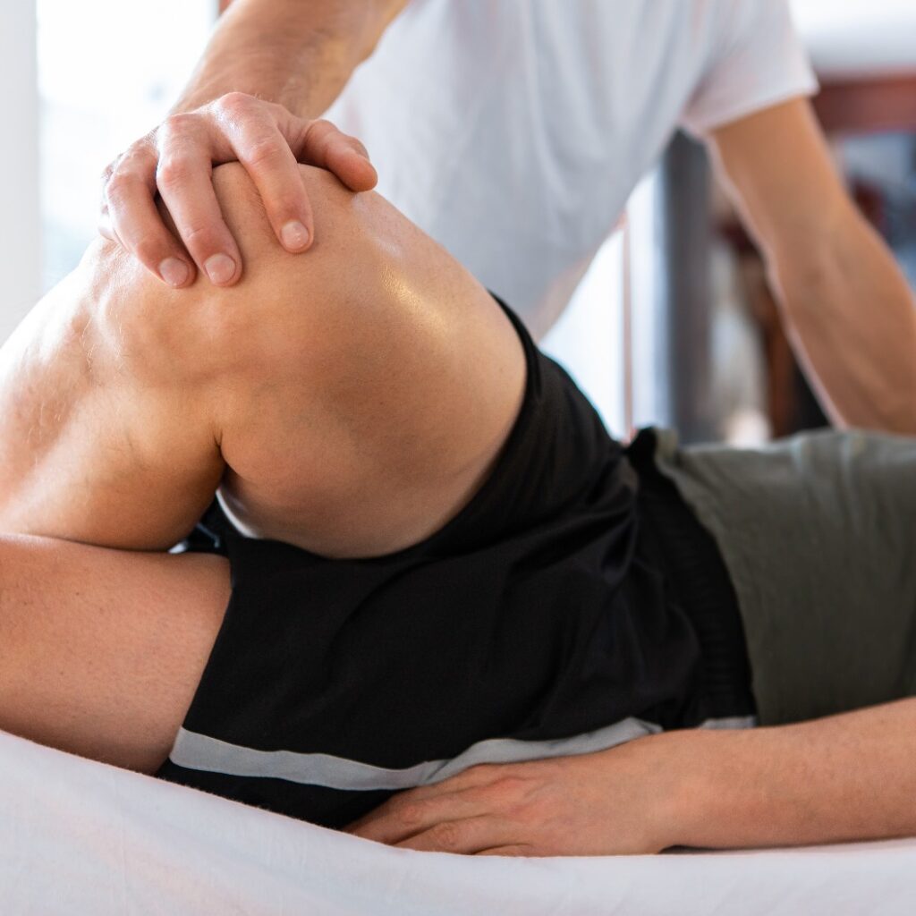Sportphysiotherapeut massiert muskulösen, kräftigen Mann